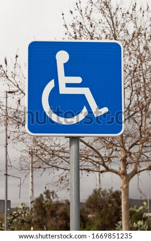 Handiccaped reserved parking lot sign with a tree on background.