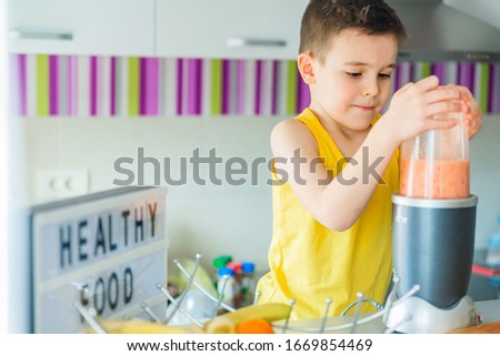Boy making a fruit smoothie at home. Portrait of a happy boy caring for his health
