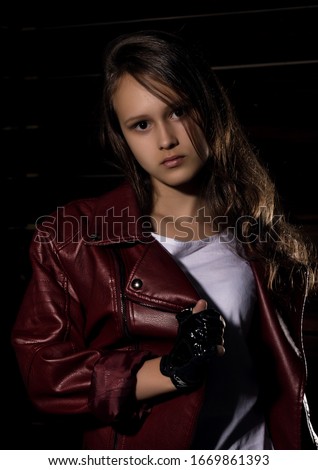 Beautyful Girl in leather jacket in a dark. Mysterious disobedient child, problems with early growing girls
