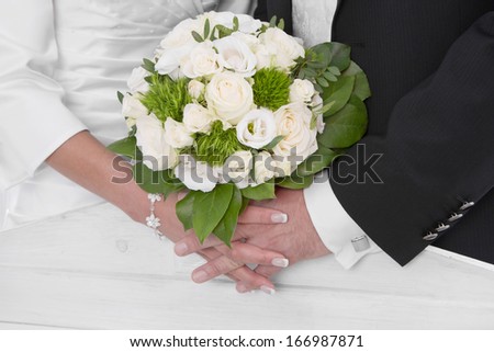 Wedding: Bride and groom holding hands with bridal bouquet