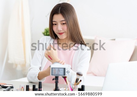 Young attractive asian woman beauty vlogger testing lipstick at the back of her hand in front of camera