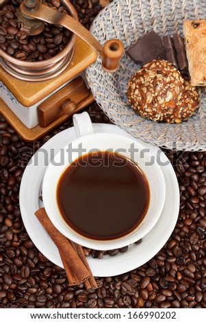 top view cup of coffee and roasted coffee beans with retro copper manual mill, biscuit, chocolate bars, cinnamon