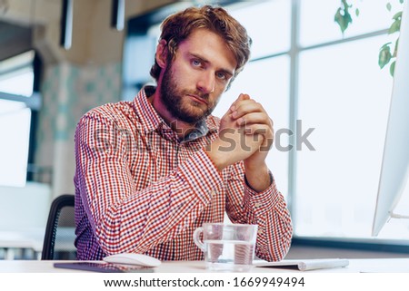 Young bearded businessman using his computer in a modern office place. Business concept