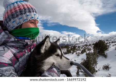 Girl with dog traveling on lift in the mountain.