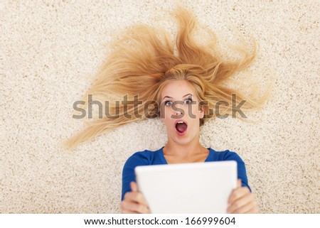 Shocked blonde woman with digital tablet 