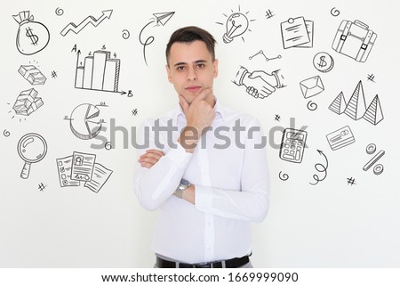 Confident businessman posing with hand drawn business sketches. Young man posing with arms folded. Handsome Caucasian man touching chin and looking at camera. Decision making concept