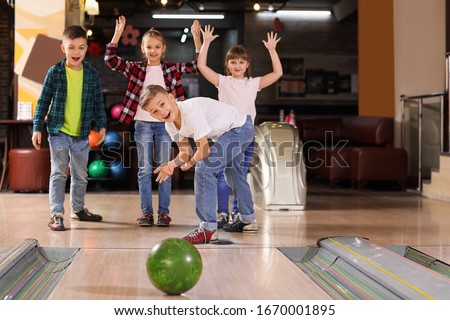 Little children playing bowling in club