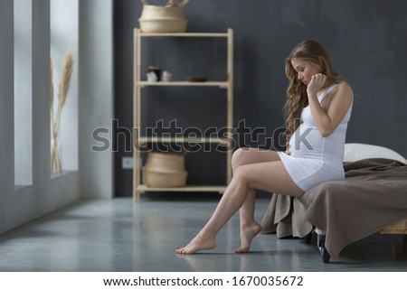 beautiful pregnant girl with long hair. Pregnancy concept. The girl gently touches her belly.