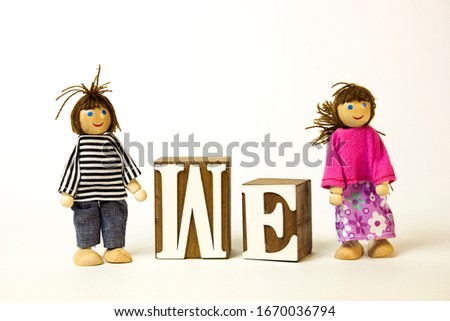 Toy wooden boy and girl stand on the background of the text we