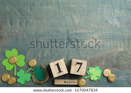 Flat lay composition with clover leaves and block calendar on light blue wooden background, space for text. St. Patrick's day