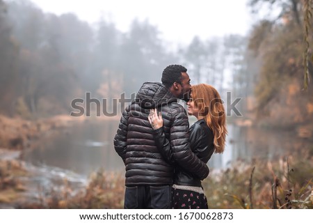 Interracial couple posing in autumn leaves background, black man and white redhead woman Royalty-Free Stock Photo #1670062873