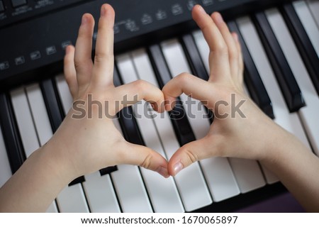 Close up of child hands making a heart over a piano