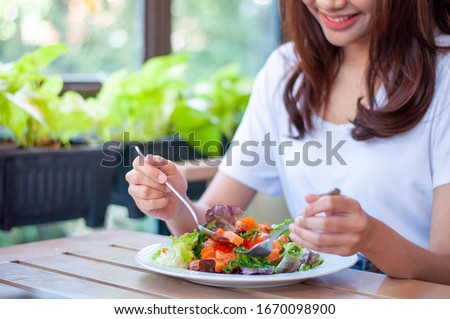 The smiling woman enjoys eating a salmon salad. To lose weight and diet, eat foods that are beneficial to the body. Weight loss concept. Royalty-Free Stock Photo #1670098900