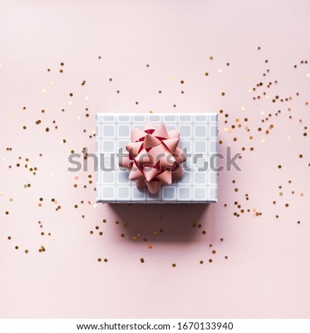 Silver gift box with pink bow and background in trendy flat lay composition with golden glitters.