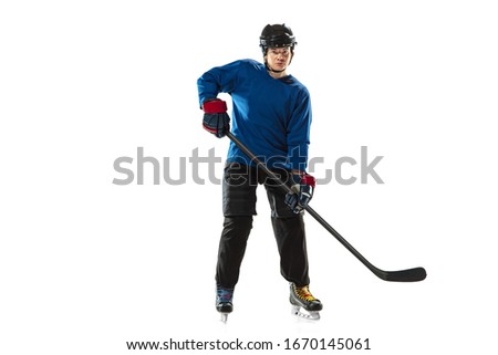 Young female hockey player with the stick on ice court and white background. Sportswoman wearing equipment and helmet training. Concept of sport, healthy lifestyle, motion, action, human emotions.