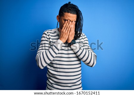 Young handsome african american afro man with dreadlocks wearing casual striped sweater rubbing eyes for fatigue and headache, sleepy and tired expression. Vision problem
