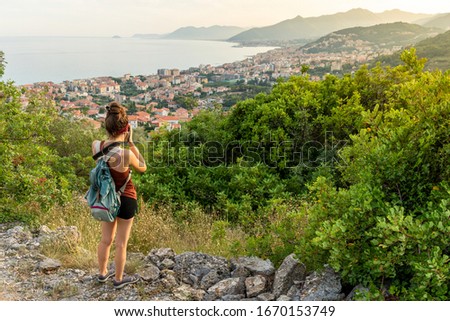 A girl in a rural scenic, walking and taking pictures on top of a hill.