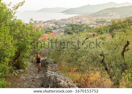 A girl in a rural scenic, walking and taking pictures on top of a hill.