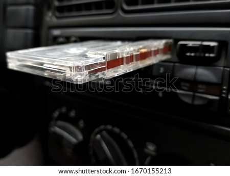 Vintage 90's cassette tape placed on a car radio cassette Royalty-Free Stock Photo #1670155213