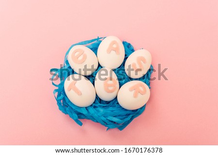 High angle view of chicken eggs with easter lettering in nest on pink background