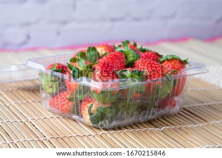 Fresh strawberries in plastic container. Vegetarian food product. Healthy fruit concept.