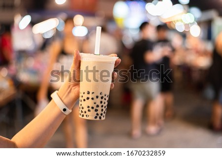 Asian woman holding the famous taiwanese bubble milk tea at night marketplace