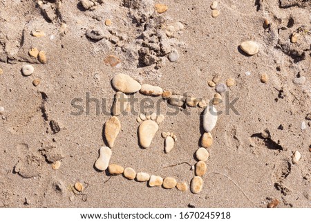 Sand texture. Sandy beach with sea  stones for background.Touching picture of sea pebbles on  sandy beach. Image of a child's and adult's foot made of stones.