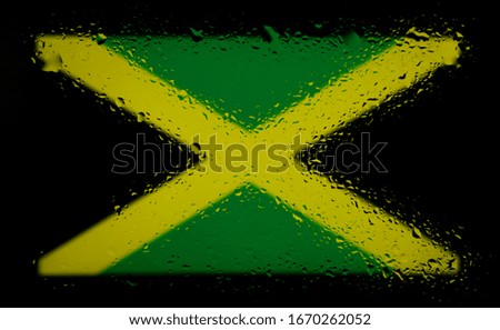 Flag of Jamaica.Abstract photo with water drops on glass.Isolated on a black background.