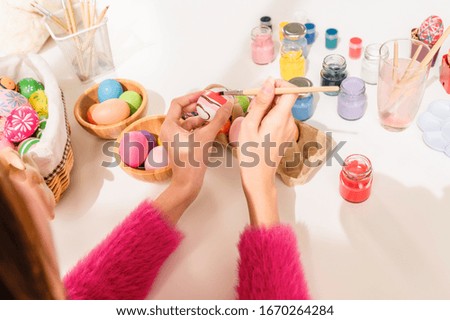 Hands of asian young woman sitting and paint easter eggs by paintbrush. Easter holiday concept.