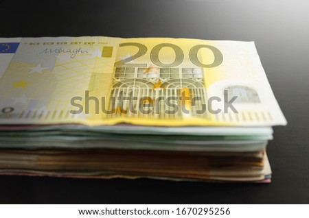 200 euro banknote. A lot of money on a black background. Image is tinted. Stack of euro. Close-up.