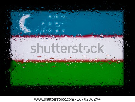 Flag of Uzbekistan. Abstract photo with water drops on glass. Isolated on black background.