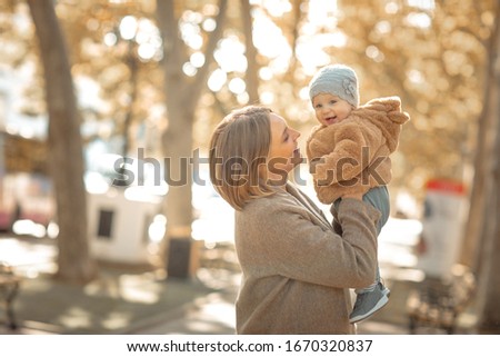 Mother and child on a walk in a public park hugs and kisses
