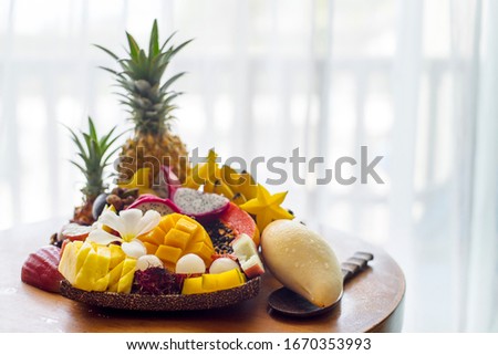 Juicy ripe tropical Thai fruits sliced and beautifully laid on a wooden dish.