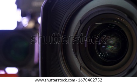 Close up of beautiful camera lens on white blurred background. Stock footage. Front element of a camera lens with beautiful color lights reflections.
