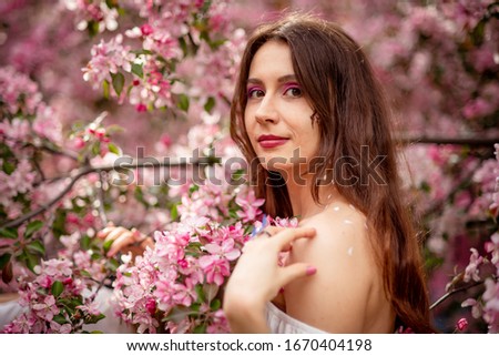young girl in a white shirt on a background of sakura flowers