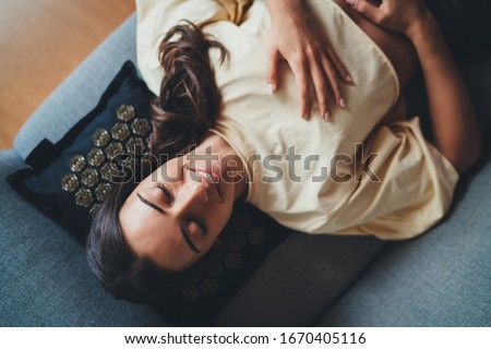 Top view of young happy beautiful woman relaxing with closed eyes on Massage Pillow ergonomic designed, fits perfectly behind neck and body contours of shoulder, Relax Wellness Healthy Lifestyle Royalty-Free Stock Photo #1670405116