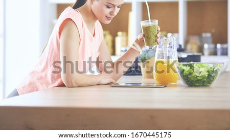 Beautiful young woman using a digital tablet in the kitchen
