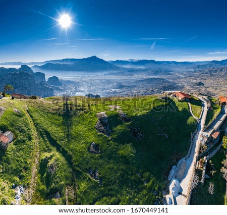 Kalambaka, Greece,  Aerial view of monastery Varlaam and breathtaking pictures of valley and landmark canyon of Meteora at sunset, Cradle on a ropeway, shadows, twisted road, bridge