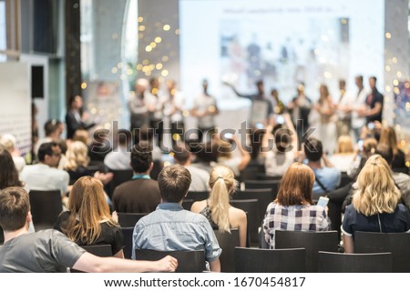 Young business team receiving award prize at best business project competition event. Business and entrepreneurship award ceremony theme. Focus on unrecognizable people in audience. Royalty-Free Stock Photo #1670454817