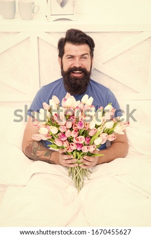 relaxing in morning. positive mood and happiness. happy bearded man in bed. birthday gift bouquet. spring fresh tulip. love valentines day. womens day. tulip flower for march 8. good morning flowers.