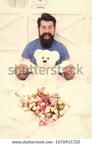 Express positivity. cheerful bearded man in bed. birthday gift. spring fresh tulip and bear toy. love valentines day. womens day. flowers for march 8. good morning surprise. happiness about present.