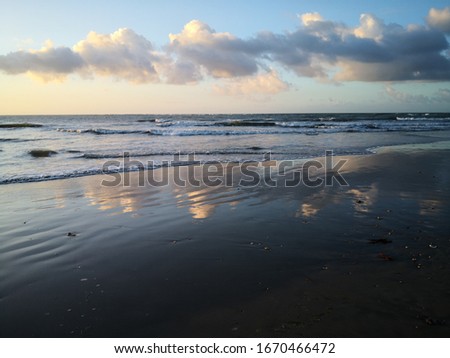 Beach view with sunset clouds and reflection. 