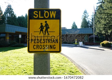 Traffic sign "Slow- pedestrian crossing" on pole.