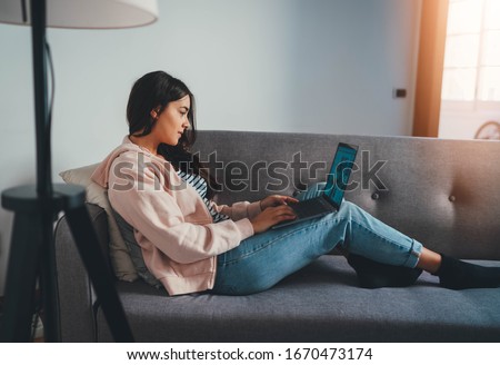 Young professional female psychologist working remotely from home sitting on sofa having online video call, Young Freelancer Woman Translator using portable computer sitting in cozy home interior