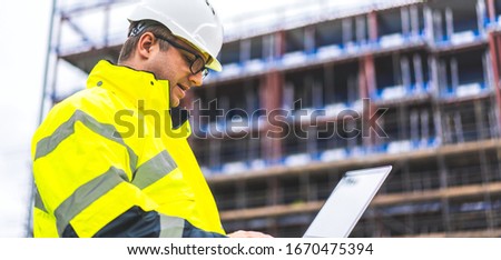 Architect inspecting site with laptop. Industrial Engineer using laptop on site. digital drawings checked on site. Metalworking and construction industry. Construction worker using laptop on site.