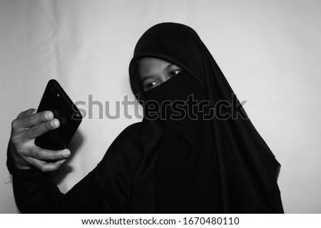 Close up view of Pretty lady woman girl wear hijab jilbab niqab kerudung niqaab scarf cover face and only show visible look of her beauty eyes. Fit for put design life image. Black white  with grain 