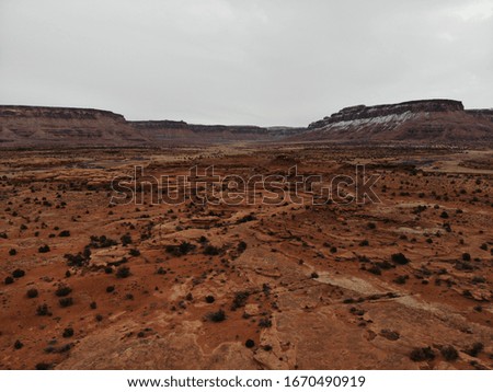 Rocky landscape with plateaus in the background under a cloudy sky. Drone shot is taken in southern Utah in a Red desert. 