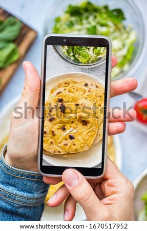 Woman hands take picture of food at home or cafe with smartphone. Phone photo of Indian chapati naan flatbread for blogging or social media. Vegan and vegetarian healthy diet.