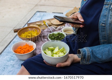 Woman hands take picture of food at home or cafe with smartphone. Phone photo of zucchini salad for blogging or social media. Vegan and vegetarian healthy diet.