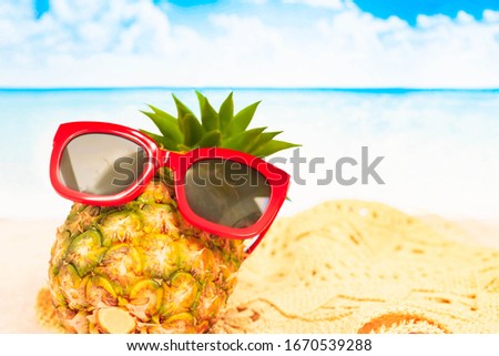 Beach,Funny pineapple in a red sunglasses and hat on the sand against sea and sky.Tropical summer vacation concept. Sunny day on the beach,Selective focus